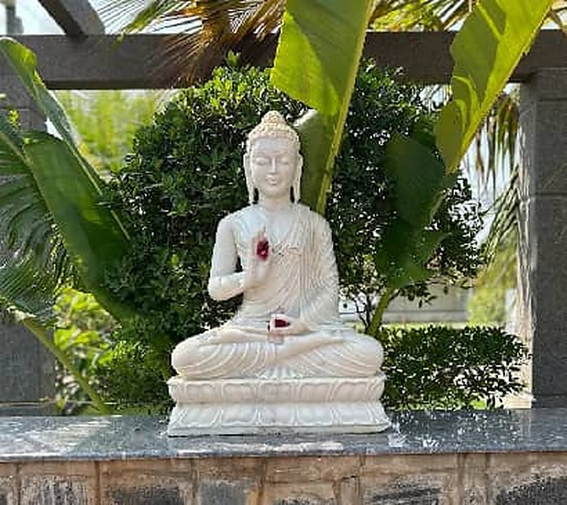 White Buddha statue in a garden corner